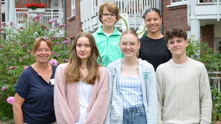 Fünf Schülerinnen und Schülern stehen während ihres Sozialpraktikums mit Pflegedienstleitung Karina Arlt (links) im Sinnesgarten der Residenz am Wiesenkamp in Hamburg-Volksdorf und lächeln beim Gruppenfoto in die Kamera Fünf Schülerinnen und Schülern stehen während ihres Sozialpraktikums mit Pflegedienstleitung Karina Arlt (links) im Sinnesgarten der Residenz am Wiesenkamp in Hamburg-Volksdorf und lächeln beim Gruppenfoto in die Kamera