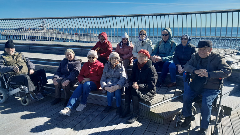 Gruppe blickt am Ostseestrand in die Kamera, Gruppenreise nach Zinnowitz an der Ostsee, Stationäre Pflege Landkreis Märkisch-Oderland, Immanuel Seniorenzentrum Kläre Weist Gruppe blickt am Ostseestrand in die Kamera bei Gruppenreise nach Zinnowitz an der Ostsee