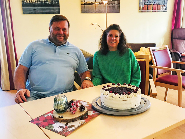 Ehepaar Hahn sitzend am Tisch, auf dem eine Schwarzwälder Kirschtorte steht, ehrenamtliches Engagement, freiwillige Mitarbeit, Albertinen Hospiz Norderstedt