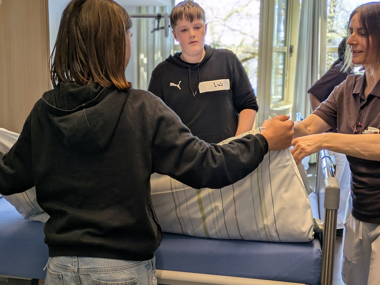 Junge hebt fertig bezogene Bettdecke an - Boys Day bei Immanuel Dienstleistungen