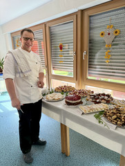 Ein Koch steht vor dem Dessertbuffet und lächelt in die Kamera bei der Feier zum 25-jährigen Jubiläum des Immanuel Suchthilfeverbunds Guben mit besonderen Wohnformen für abhängigkeitskranke Menschen in Thüringen