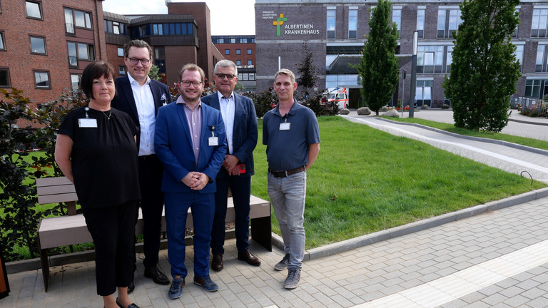 Team mit dem Vorsitzenden der Konzerngeschäftsführung, Matthias Scheller, und Krankenhausgeschäftsführer Christian Rilz bei einer Ruhebank der neuen Zuwegung, Albertinen Krankenhaus, Hamburg-Schnelsen Ein Team mit dem Vorsitzenden der Konzerngeschäftsführung, Matthias Scheller, und Krankenhausgeschäftsführer Christian Rilz steht vor einer Ruhebank der neuen Zuwegung des Albertinen Krankenhauses in Hamburg-Schnelsen