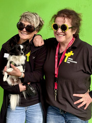 Zwei Mitarbeiterinnen lachen in einer Fotobox mit Sonnenbrillen und Hund in die Kamera beim Festakt zum 25-jährigen Jubiläum des Immanuel Suchthilfeverbunds Guben mit besonderen Wohnformen für abhängigkeitskranke Menschen in Thüringen