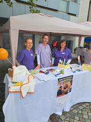Drei Mitarbeiterinnen in Funktionskleidung blicken am Stand des Immanuel Klinikums Bernau Herzzentrum Brandburg beim Gesundheitstag in Bernau b. Berlin in die Kamera