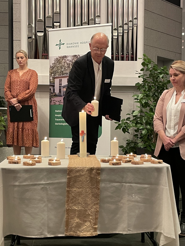 Ein Angehöriger zündet eine Kerze in der Kirche an, Gottesdienst in Gedenken an die Verstorbenen, Ambulanter Hospizdienst, stationäres Hospiz, Diakonie Hospiz Wannsee, Berlin