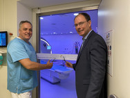 Chefarzt Prof. Christoph Weber und Geschäftsführer Andreas Schneider schneiden das Band vor dem dunkelblau illuminierten Raum mit dem neuen MRT-System im Immanuel Albertinen Zentrum für Radiologie am Standort Ev. Amalie Sieveking Krankenhaus in Hamburg durch