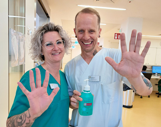 Mitarbeiterin und Mitarbeiter zeigen Hände und halten Desinfektionsmittel Mitarbeiterin und Mitarbeiter zeigen Hände und halten Desinfektionsmittel