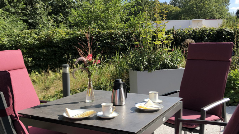 Blick auf einen gedeckten Tisch und Stühle auf der Terrasse, Hospiz in Hamburg und Umgebung, Spenden und Ehrenamt, Forderung Sparkasse Stiftung Südholstein, Albertinen Hospiz Norderstedt Blick auf einen gedeckten Tisch und Stühle auf der Terrasse im Albertinen Hospiz Norderstedt