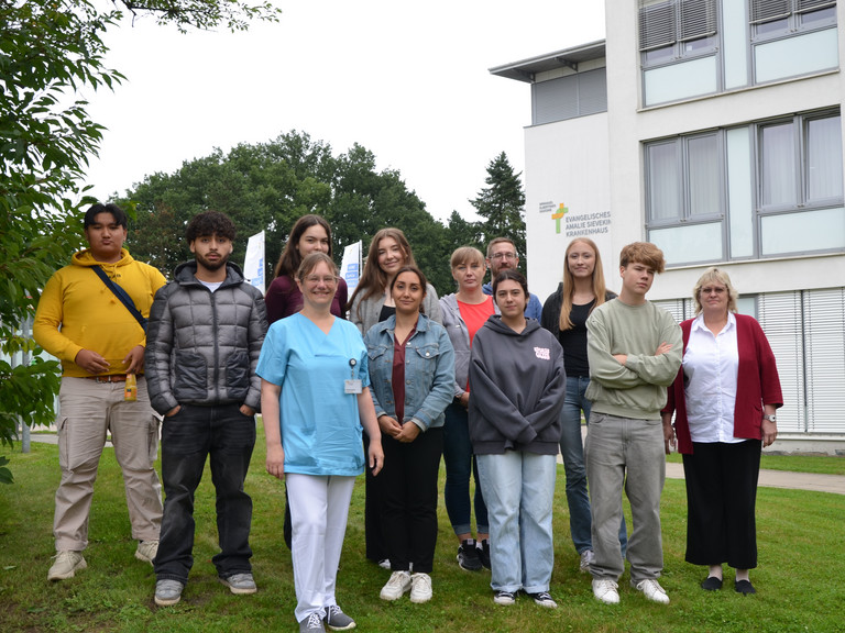 Gruppenfoto im Freien mit neuen Auszubildenden des Jahrgangs 2025 und Ausbildungsverantwortlichen auf dem Gesundheitscampus Volksdorf vor dem Evangelischen Amalie Sieveking Krankenhaus in Hamburg-Volksdorf