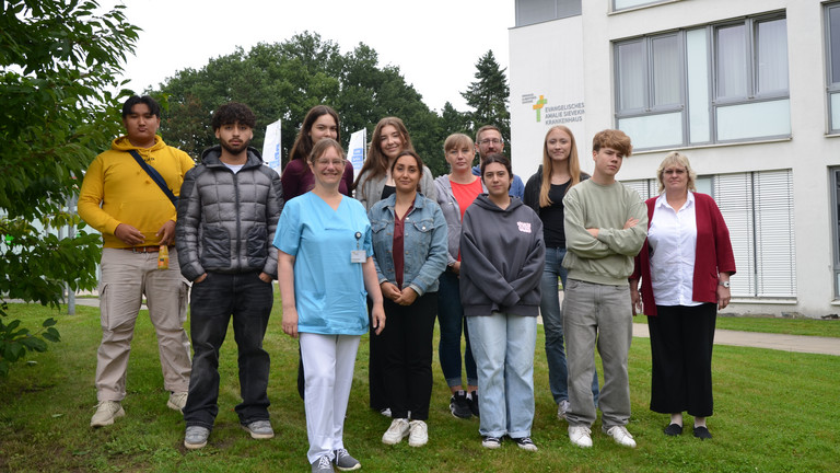 Gruppenfoto im Freien mit neuen Auszubildenden des Jahrgangs 2025 und Ausbildungsverantwortlichen auf dem Gesundheitscampus Volksdorf vor dem Evangelischen Amalie Sieveking Krankenhaus in Hamburg-Volksdorf