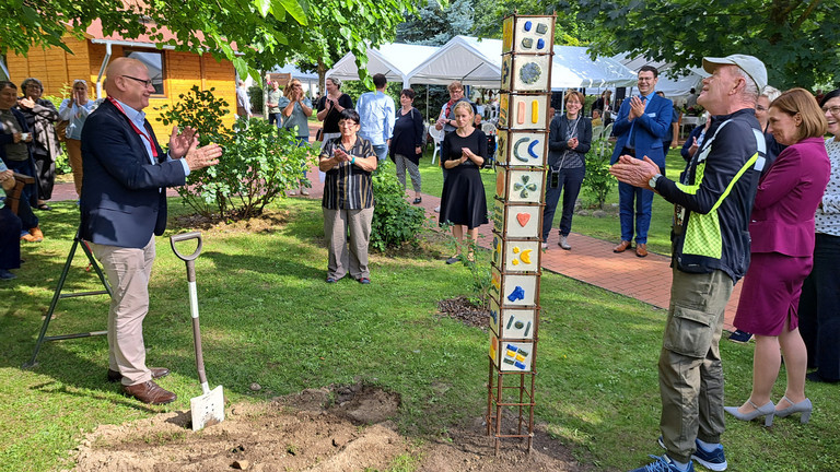 Geschäftsführer Herbert Blum (links) hat für die Nachwelt eine Zeitkapsel bei der von Bewohnenden gestalteten Stele vergraben. Geschäftsführer Herbert Blum (links) hat für die Nachwelt eine Zeitkapsel bei der von Bewohnenden gestalteten Stele vergraben.