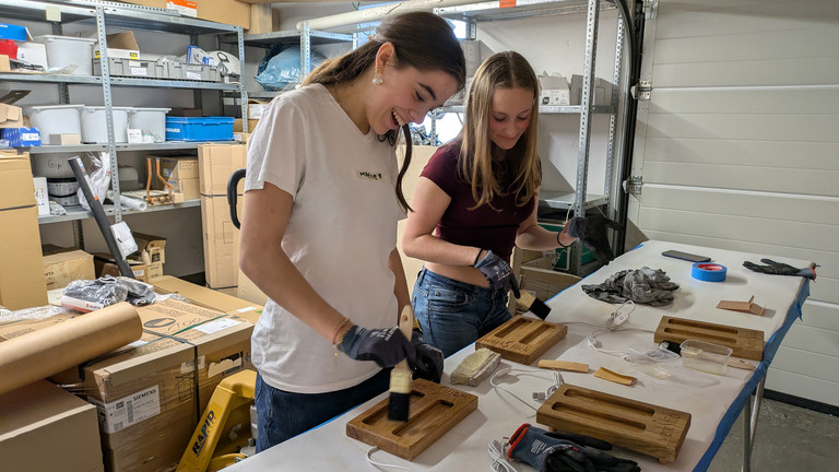 Mädchen haben Spaß beim Auftragen von Holzöl auf Handyhalter - Werkstück Raumgestaltung & Versorgungstechnik Mädchen haben Spaß beim Auftragen von Holzöl auf Handyhalter - Werkstück Raumgestaltung & Versorgungstechnik