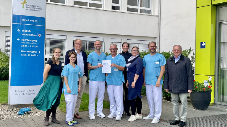 Mitarbeitende der Klinik für Anästhesiologie und Intensivmedizin zusammen mit Mitarbeitende der Ärztekammer Hamburg vor dem Krankenhaus mit dem Zertifikat in der Hand, Qualitätssicherung erfolgreich bestanden, Auszeichnung, Hamburg-Volksdorf Mitarbeitende der Klinik für Anästhesiologie und Intensivmedizin zusammen mit Mitarbeitende der Ärztekammer Hamburg vor dem Krankenhaus mit dem Zertifikat in der Hand, Qualitätssicherung erfolgreich bestanden, Auszeichnung, Hamburg-Volksdorf