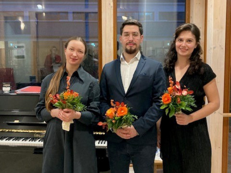 Daria Podushko, Laurence Kalaidjian, und Yekaterina Badeso stehen mit Blumen vorm Klavier, Live-Musik im Hospiz, Konzert für Hospiz-Gäste, Diakonie Hospiz Norderstedt