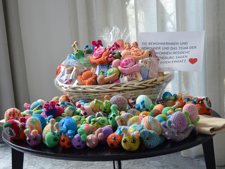 Gehäkelte Neskenschnecken in einem Korb auf einem Tisch Gehäkelte Neskenschnecken in einem Korb auf einem Tisch