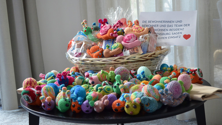 Gehäkelte Neskenschnecken in einem Korb auf einem Tisch Gehäkelte Neskenschnecken in einem Korb auf einem Tisch