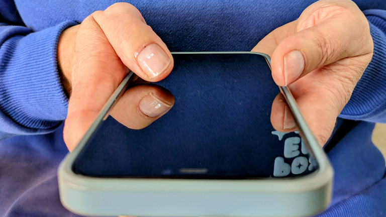 Person hält Smartphone in den Händen und hält beide Daumen auf Bildschirm Person hält Smartphone in den Händen und hält beide Daumen auf Bildschirm