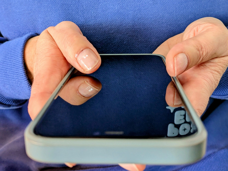 Person hält Smartphone in den Händen und hält beide Daumen auf Bildschirm Person hält Smartphone in den Händen und hält beide Daumen auf Bildschirm