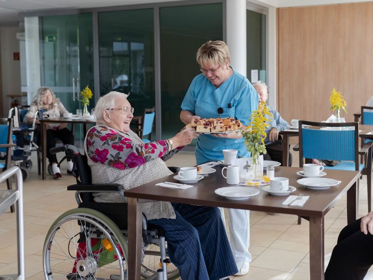 Serviceassistentin reicht Seniorin Kuchen - Immanuel Dienstleistungen sucht Küchen- und Servicekraft für Seniorenzentrum in Elstal